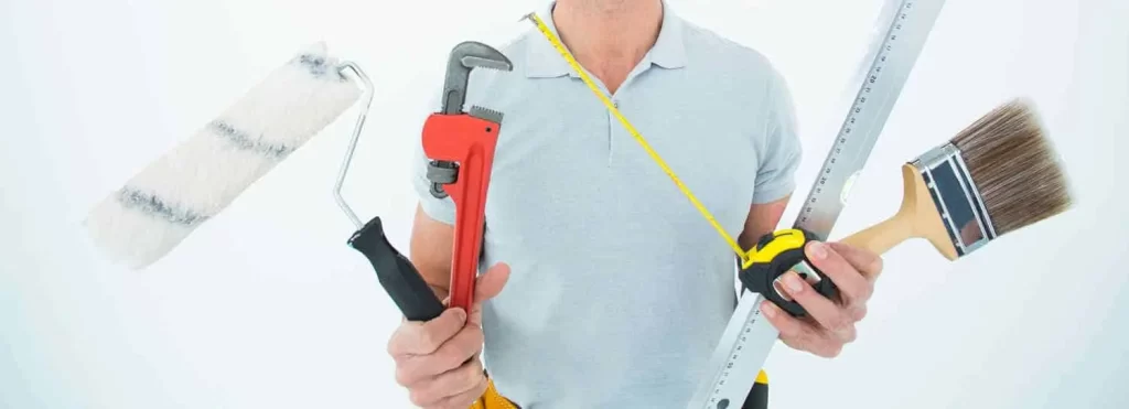 man's chest showing his hands holding various building and decorating tools