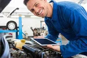 Mechanic holding a computer table analysing a car