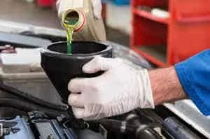 mechanic topping up car coolant system