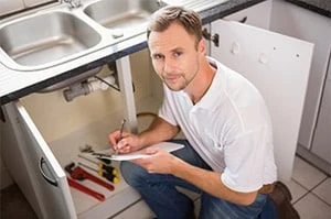 plumber inspecting under a new sink in the kitchen